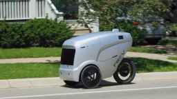 A futuristic-looking, three-wheeled, autonomous delivery robot by Refraction AI.